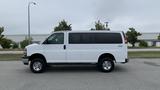 A white 2017 Chevrolet Express Quigley 4x4 van viewed from the side showcasing its elongated body and chrome wheels