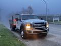 A 2015 Ford F-550 truck with a flatbed and orange marker lights visible on the roof