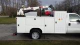 A 2010 Ford F-550 utility truck with a mounted crane and tool compartments on the side