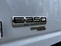 A close-up view of a chrome badge on a white 2014 Ford Econoline featuring the model E-350 XLT Super Duty and an AdvancedTrac RSC label