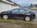 A black 2016 Chrysler 200 sedan parked on a driveway with its doors closed and windows rolled up