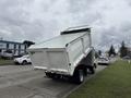 A white 2014 Hino 195 truck with a dump bed elevated at an angle